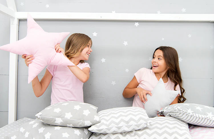 Zwei Kinder spielen mit sternförmigen Kissen – für Familien und gemütliche Momente